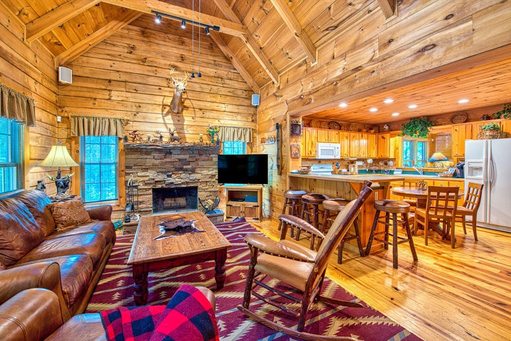 Great room in a Highlands NC vacation rental with vaulted log walls, leather seating, and wood-burning fireplace