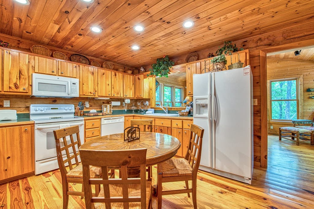 Fully equipped main kitchen with warm wood cabinetry and a round breakfast table