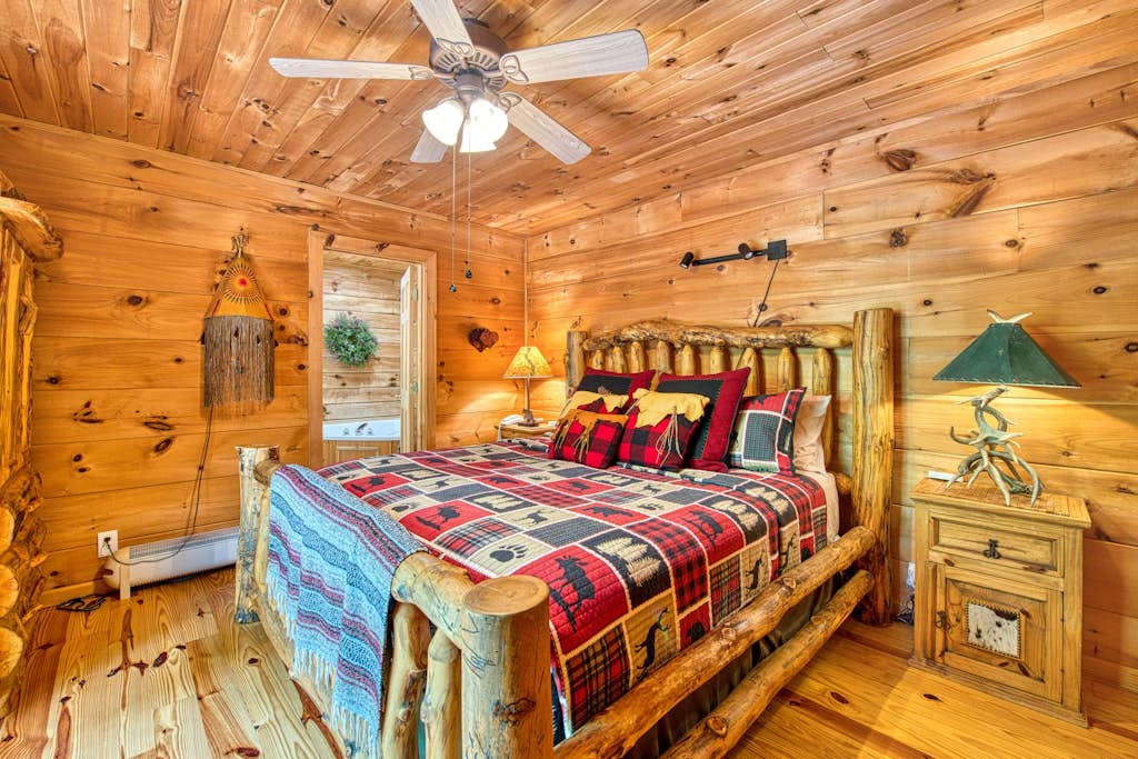 Main-level bedroom with a log bed, colorful mountain bedding, and wood-paneled walls